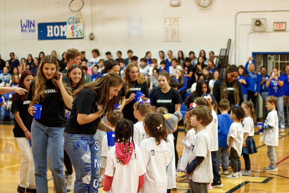 Seniors give welcome gifts to kindergarteners at the Homecoming pep rally.