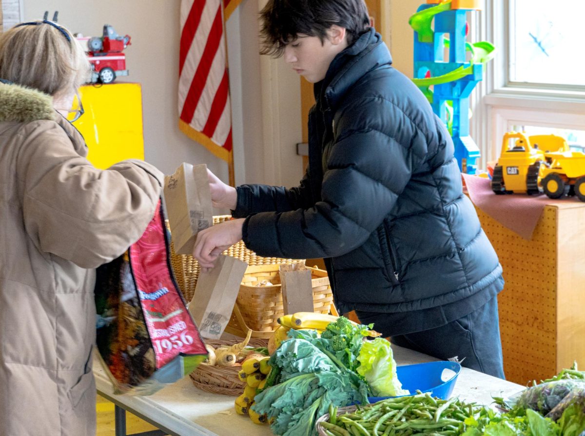 Haldane Freshman Max Robohm assists a client at the Philipstown Food Pantry tables in the First Presbyterian Church in Cold Spring on January 11th. 