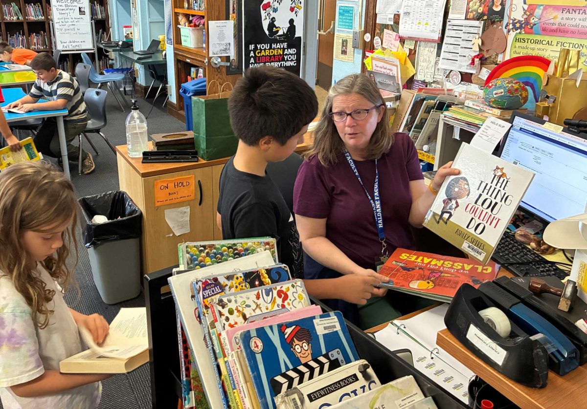 Librarian Carolyn Llwellyen helps students check out their books in the Haldane Elementary Library on October 7, 2025.