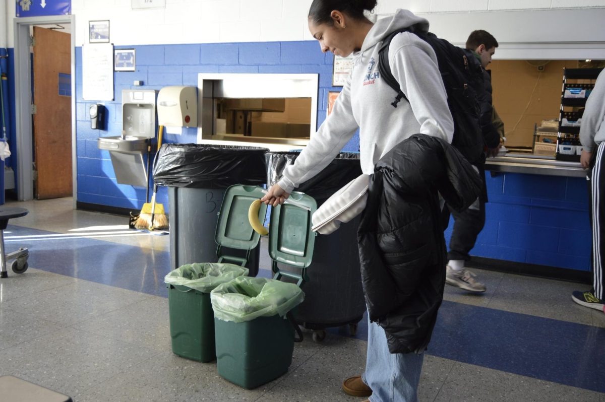 Sophomore Anya Mercurio places food waste into a compost bin during lunch in the school cafeteria. The composting program, initiated by the Habitat Revival Club, reduces cafeteria waste by separating food scraps from regular trash.